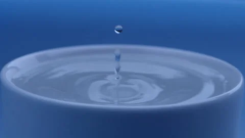 Water drop falls into the filled cup on blue background in slow motion. Stock Footage 142884931