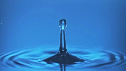Water drop splash forming beautiful crown shape in blue liquid Stock Footage 310230349