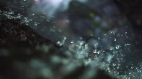 Water droplets and spray flowing and splashing on rock at waterfall. Close up. Stock Footage