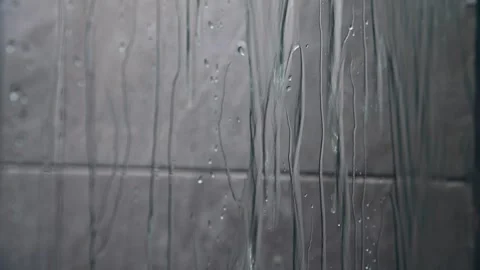 Water droplets cascade down a glass surface, creating a mesmerizing flow pattern Stock Footage 330940041