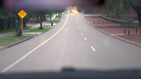 Water droplets diffuse headlights giving dream like affect to long focal Stock Footage 257875398