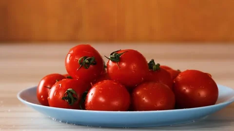 Water droplets dripping down a variety of cherry tomatoes on a blue plate. Stock Footage