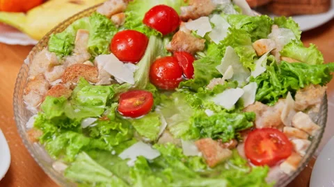 Water droplets dripping onto a fresh Caesar salad on a table Stock Footage 339413833