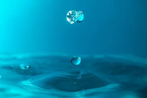 Water droplets fall down closely into the blue water, making it the perfect.. Stock Photos