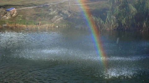Water droplets fall onto the surface of the water. Rainbow in sunbeams. Stock Footage 142282003