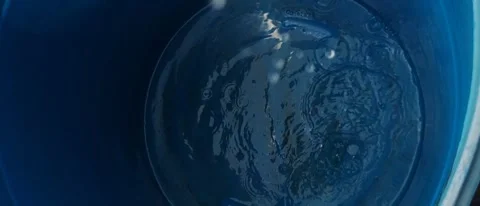 Water Droplets Falling into Blue Basin Creating Ripples and Bubbles Video stock 334368612