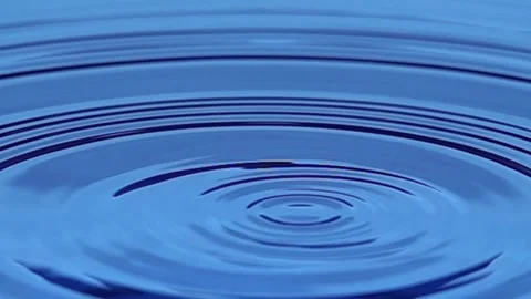 Water droplets falling into blue liquid creating gentle concentric ripples Stock Footage 336400421