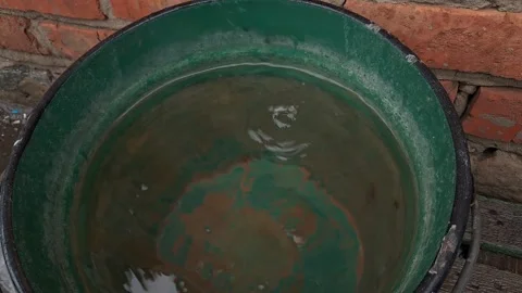 Water droplets falling into green bucket creating ripples. Stock Footage 329665949