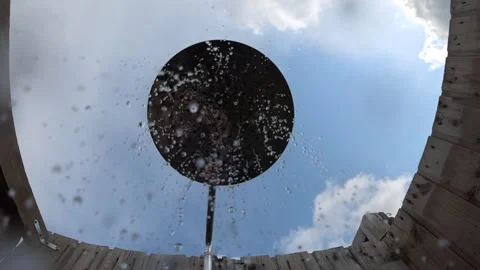 Water droplets falling from a large round shower head, framed by a wooden Stock Footage 342987666