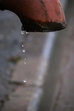 Water droplets flow from old rusty pipe. Water scarcity on planet. Concept of Stock Photos
