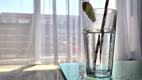 Water Droplets Flowing Down Cold Glass of Refreshing Water with Lemon and Straw Stock Footage 340332650