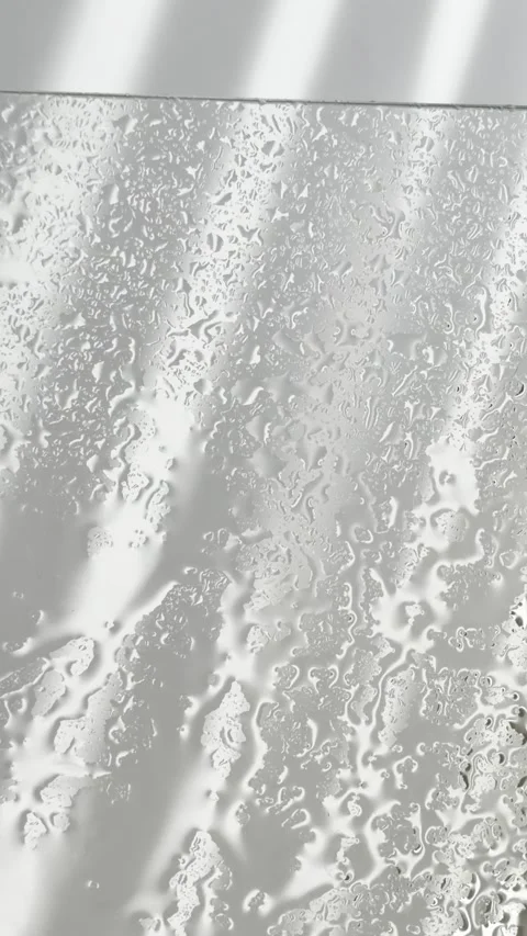 Water droplets flowing down a wet shower glass panel with sunlight and shad.. Stock Footage 335139394