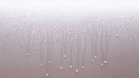 Water droplets moving slowly down a brightly lit kitchen wall Stock Footage 326812079