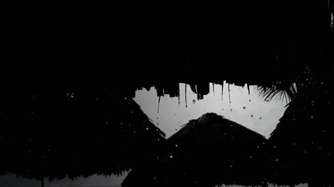 Water droplets pour around silhouetted thatched umbrellas- a Caribbean rainstorm Stock Footage 142823853