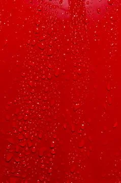 Water droplets on a red surface create patterns Stock Photos