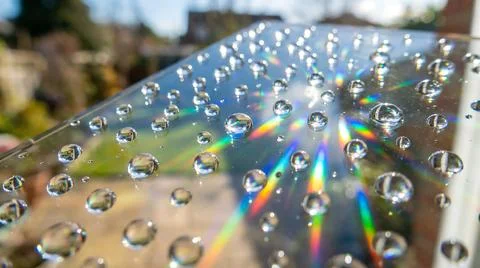 Water droplets on transparent surface creating rainbow light refraction Stock Photos