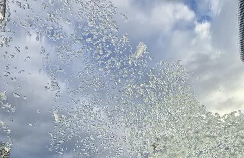 Water droplets on a window create a dynamic pattern against a cloudy sky, Stock Photos