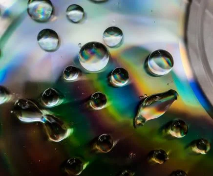 Water is dropping on the CD discs and red, blue and yellow lights are coming Stock Photos