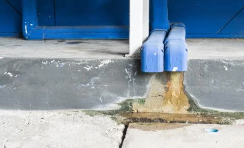 Water dropping from plastic drain pipe, moss on the floor, copy space for tex Stock Photos