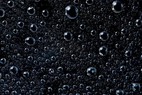 Water drops on black surface Stock Photos