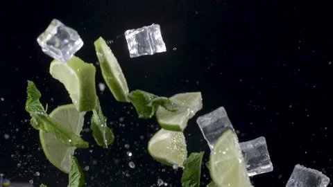 Water drops, chunks of lime and mint fly up, on a black background, close-up Видео 144334522