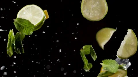 Water drops, chunks of lime and mint fly up, on a black background, close-up Stock Footage 144334536