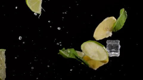 Water drops, chunks of lime and mint fly up, on a black background, close-up Stock Footage 144334547