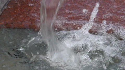 Water drops close-up that fall on the granite stone in the city fountain. Video stock 111424885