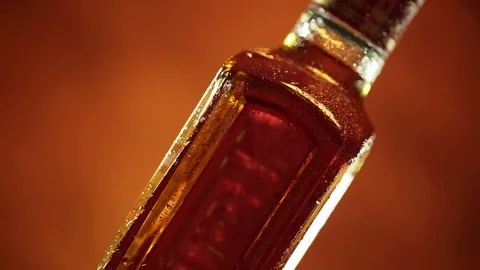 Water drops on the cooled bottle of brandy or whiskey on brown background Vídeo Stock 96238634