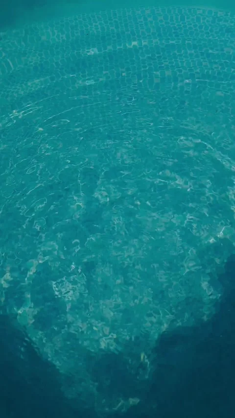 Water drops creating circular ripples on turquoise swimming pool surface in Stock Footage 341314227