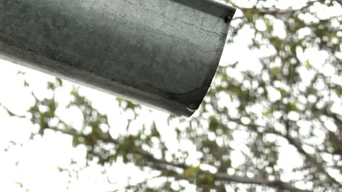 Water Drops Drip From A Metal Gutter With Green Trees In The Background Stock Footage 334036966