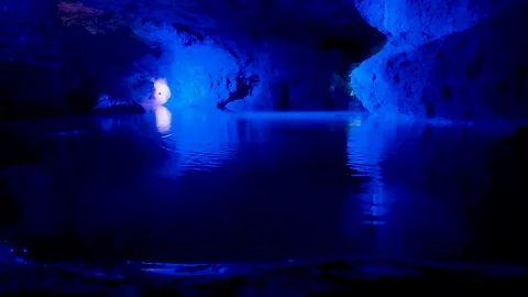 Water drops dripping in a blue illuminated cave pool Stock Footage 345644961