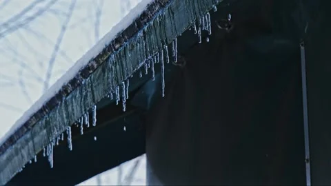 Water Drops Dripping from Tiny Icicles Melting on Edge of Roof Covered in Snow  Video stock 258670923