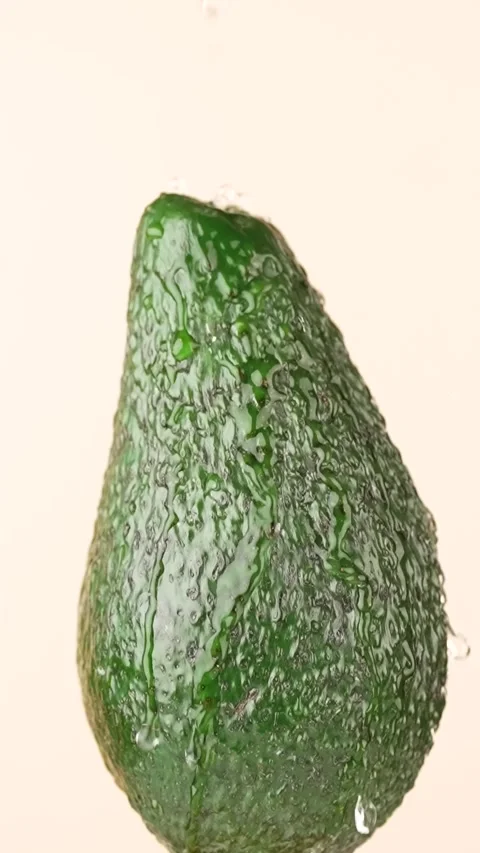 Water drops fall on avocado on a beige background, slow motion, vertical vi.. Stock Footage 304993424