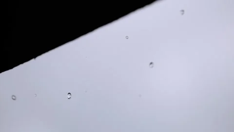 Water drops fall from edge of roof, in super slow motion, white background 4k Stock Footage 204032027