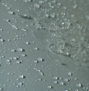 Water drops fall on a light gray background. Closeup Stock Photos