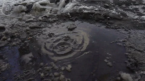 Water drops fall in slow motion into a muddy puddle Stock Footage 166162418