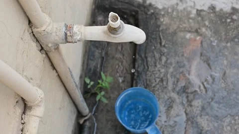 Water drops falling down from a broken tap into a cup in a village in pakistan Stock Footage 157197342