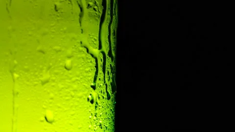 Water drops falling down on the glass of beer. Water drops on green glass Stock Footage 155798249
