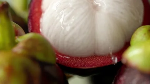 Water drops falling from half opened fresh mangosteen,  white flesh fruit Stockbeeldmateriaal 318377000