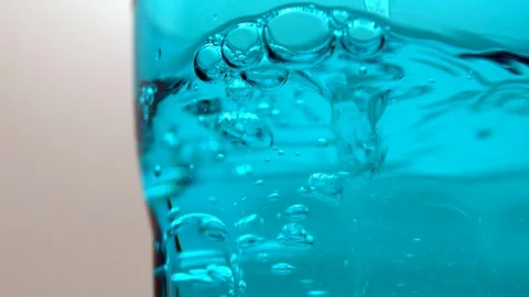 Water drops falling inside blue crystal glass on white background Stock Footage 108803514