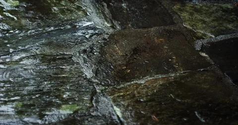Water drops falling on an old granite stone floor with puddles of water Stock Footage 98054948
