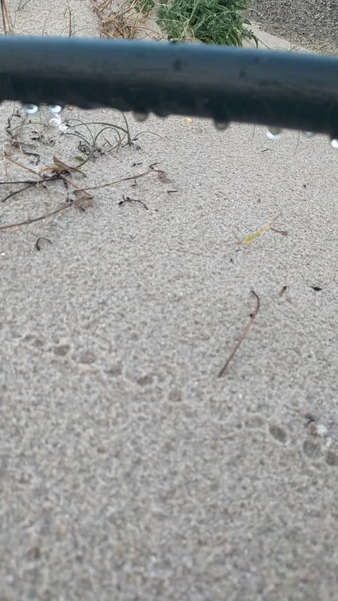 Water drops falling from pipe onto sandy beach Stock Footage 327190649