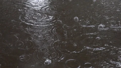 Water drops falling into puddle on asphalt. Stockbeeldmateriaal 98235843