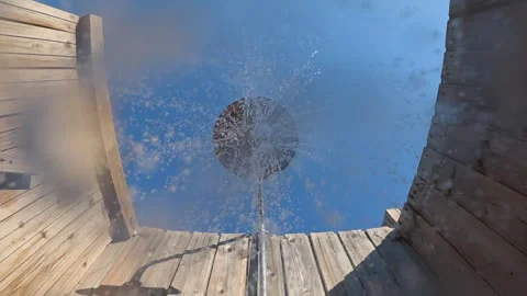 Water drops falling from a shower head against a clear blue sky and wooden Stock Footage 342885740