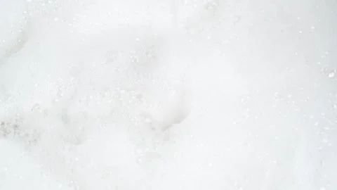 Water drops falling in white foam, top view. Soap foam texture surface back.. Stock Footage 274552126