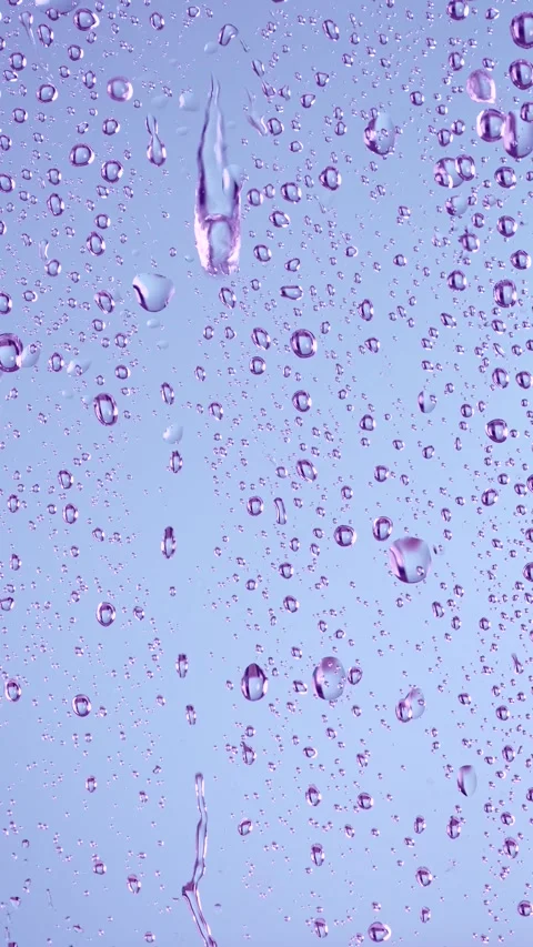 Water drops falling on window glass on light purple background. Stock Footage 307305038