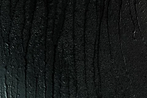 Water drops on flat black rubber surface macro background with smudges Foto stock