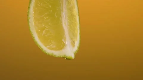 Water drops into the lime on the orange background. 4k footage Stock Footage 201342360