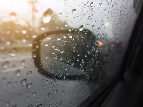 Water drops on a window in the heavy rain. View of car on the street. Stock Photos